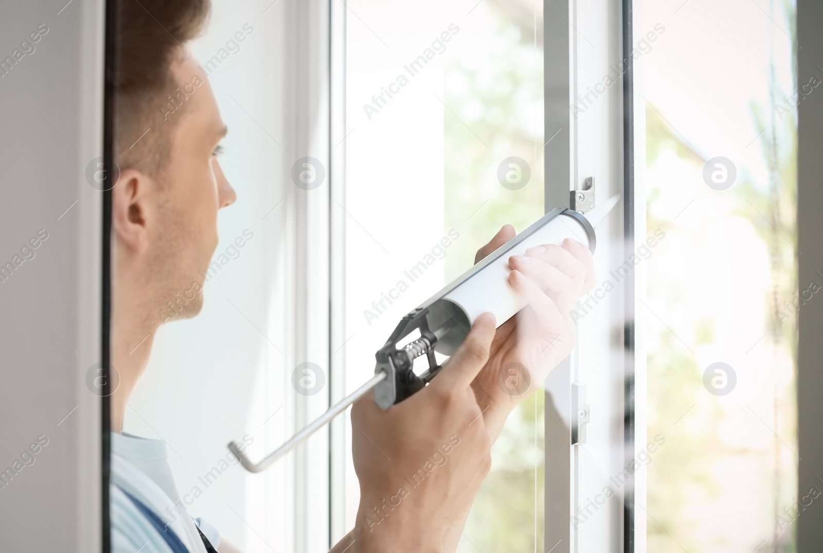 Photo of Construction worker sealing window with caulk indoors