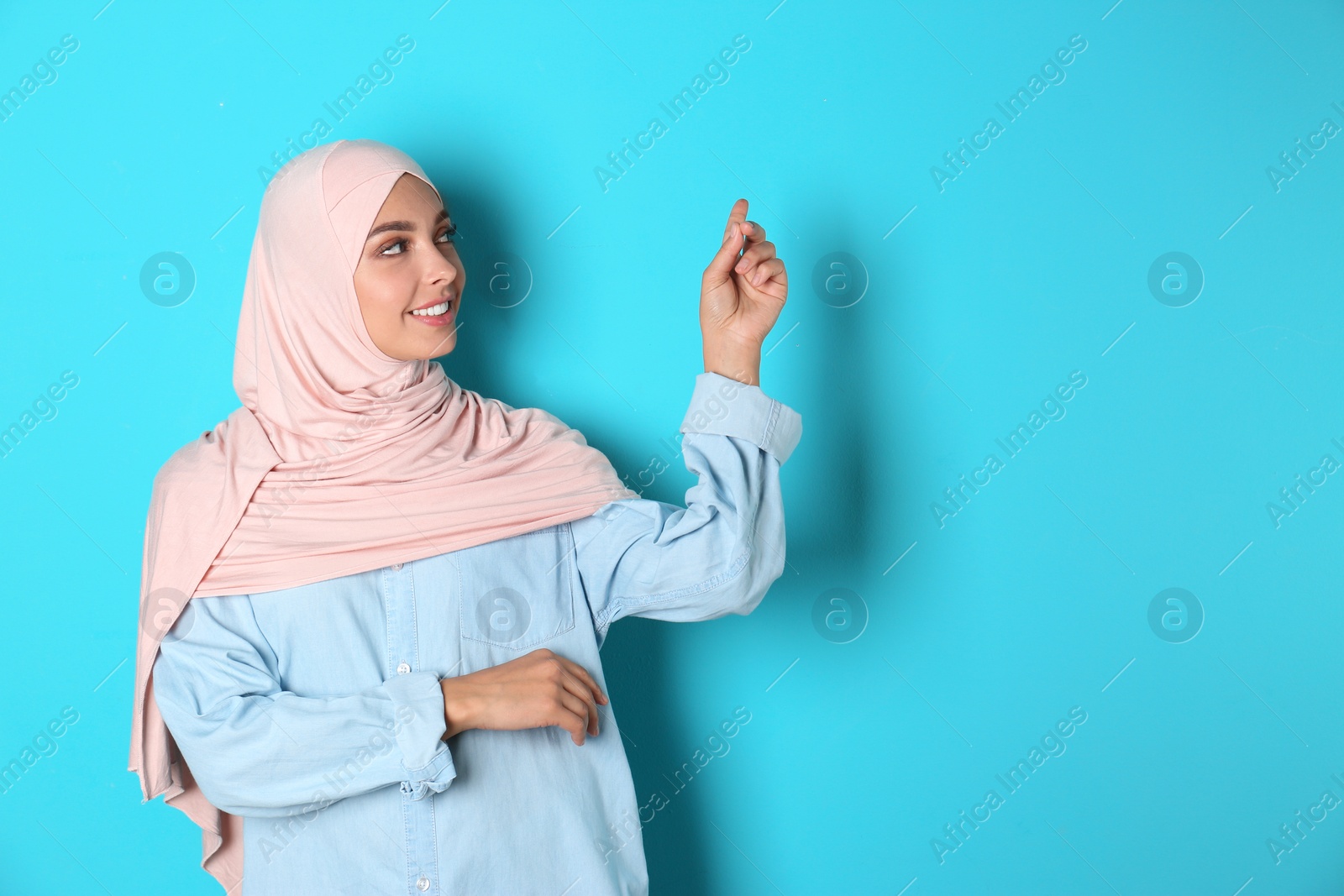 Photo of Portrait of young Muslim woman in hijab against color background. Space for text