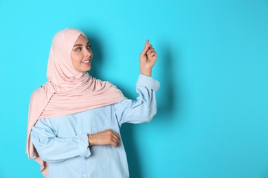 Portrait of young Muslim woman in hijab against color background. Space for text