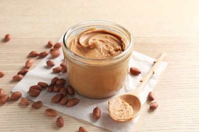 Photo of Jar and spoon with creamy peanut butter on table