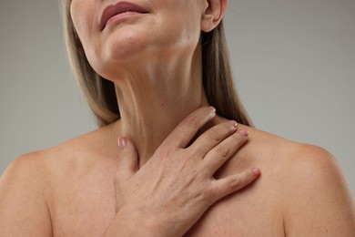 Mature woman with healthy skin on grey background, closeup