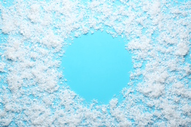 Frame made of snow on blue background, top view with space for text. Winter season