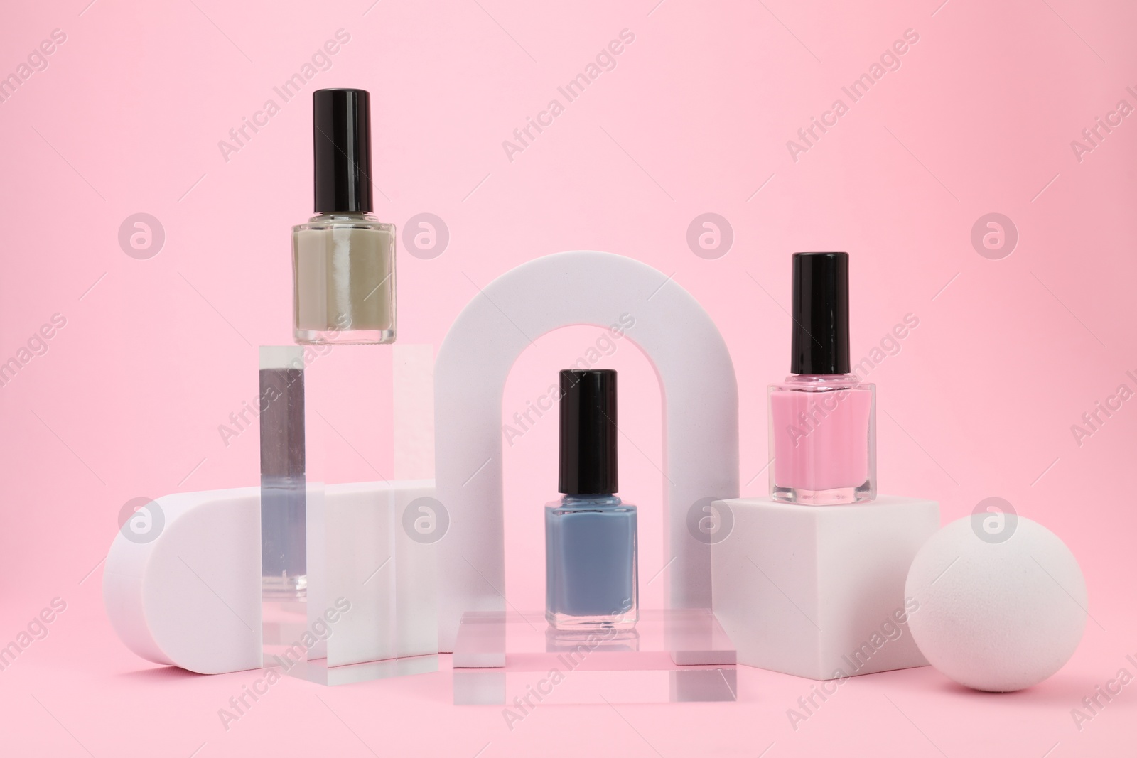 Photo of Stylish presentation of nail polishes on pink background