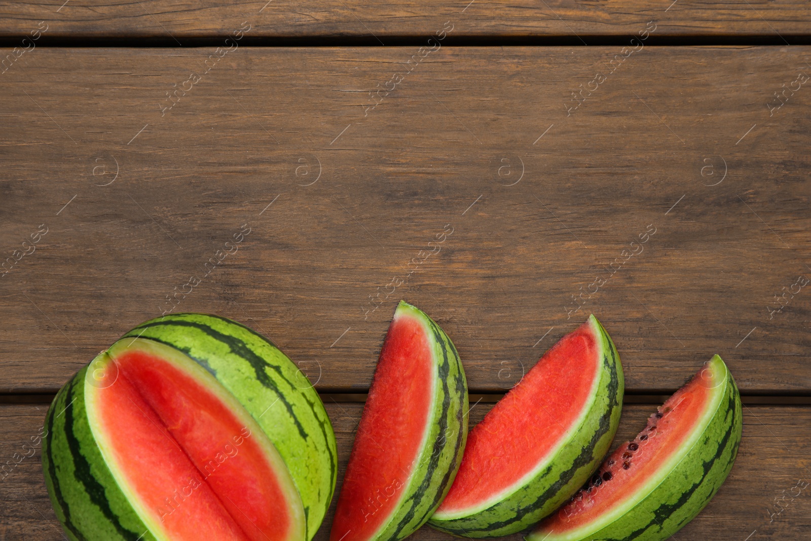 Photo of Delicious cut watermelons on wooden table, flat lay. Space for text