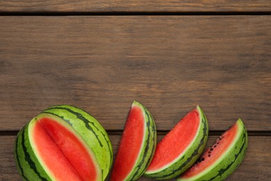 Delicious cut watermelons on wooden table, flat lay. Space for text