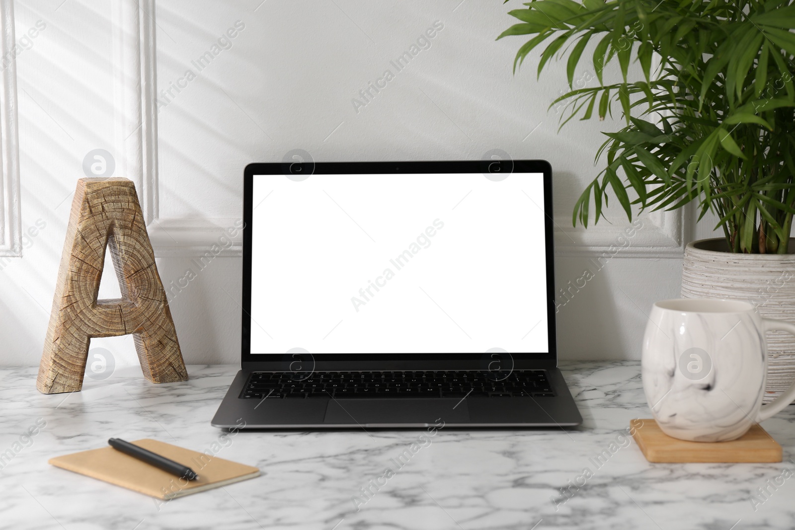 Photo of Office workplace with computer, glasses, cup and stationery on marble table near white wall