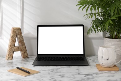 Photo of Office workplace with computer, glasses, cup and stationery on marble table near white wall