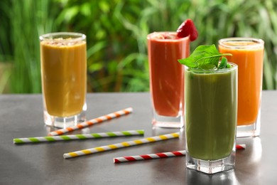 Photo of Many different delicious smoothies on grey table against blurred background