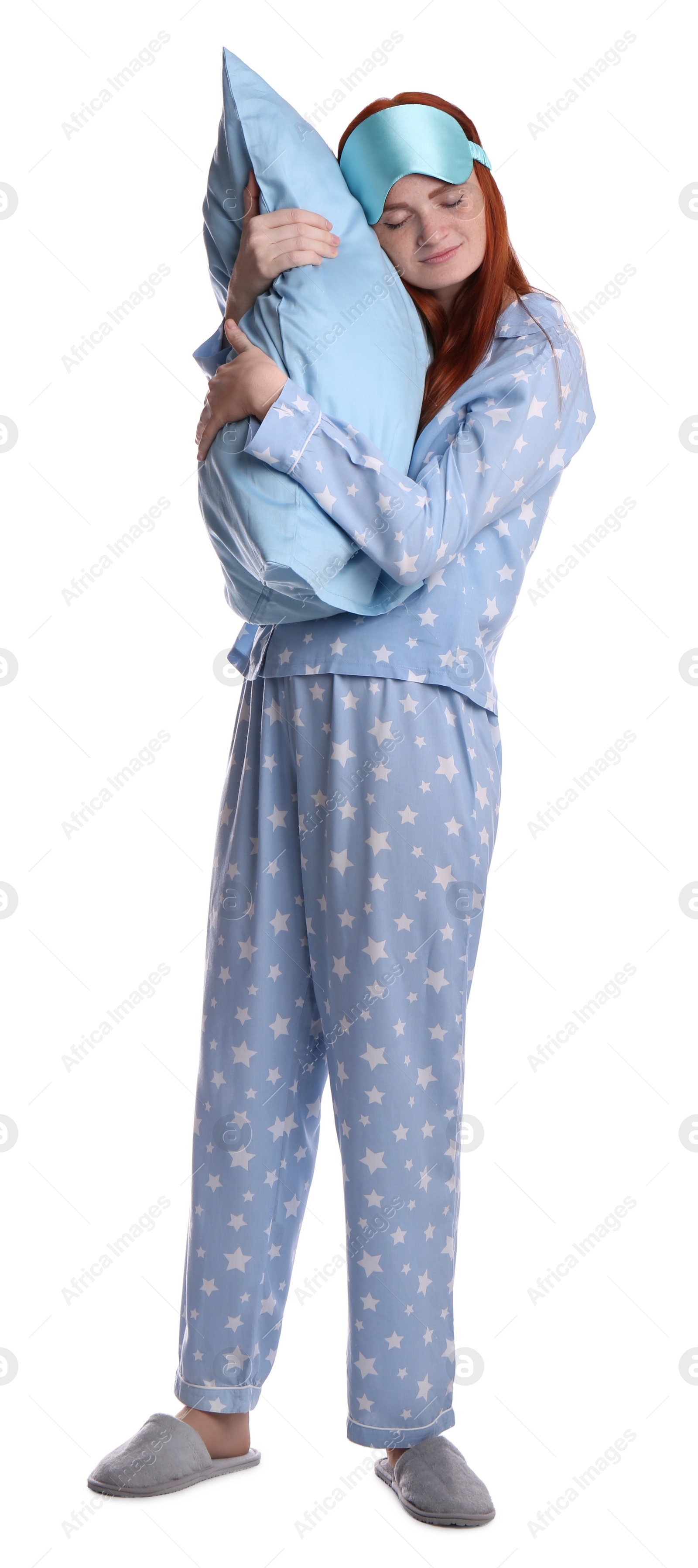 Photo of Young woman wearing pajamas and slippers with pillow in sleepwalking state on white background