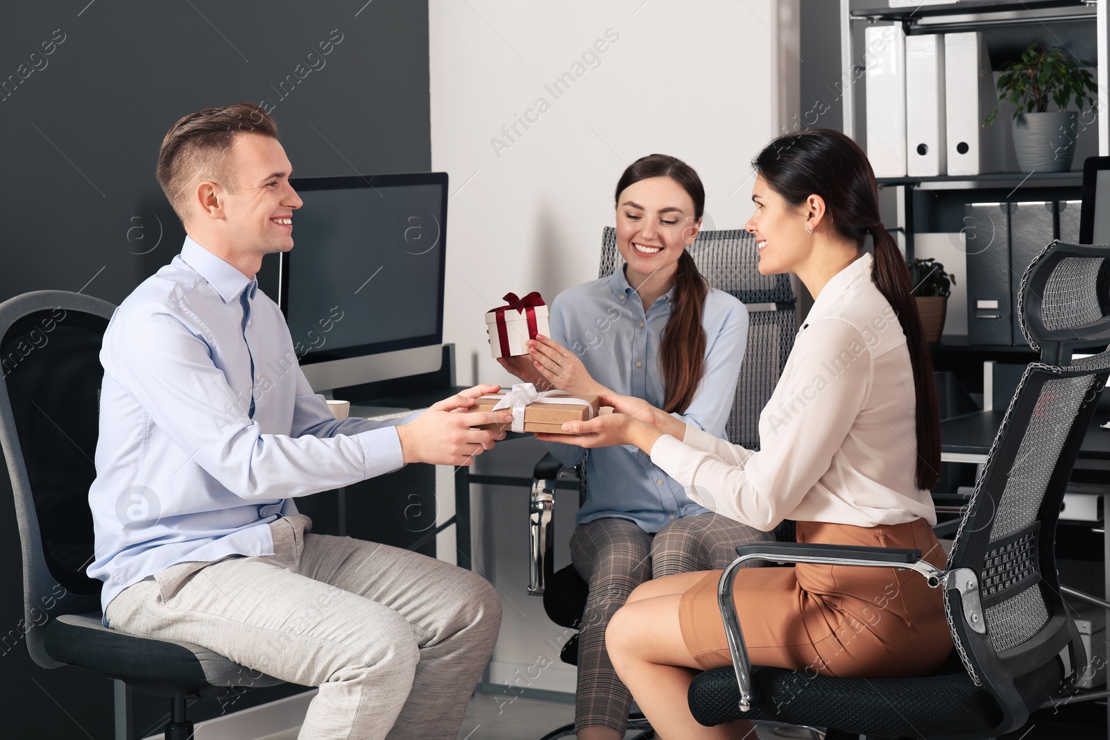 Photo of Colleagues presenting gifts to woman in office