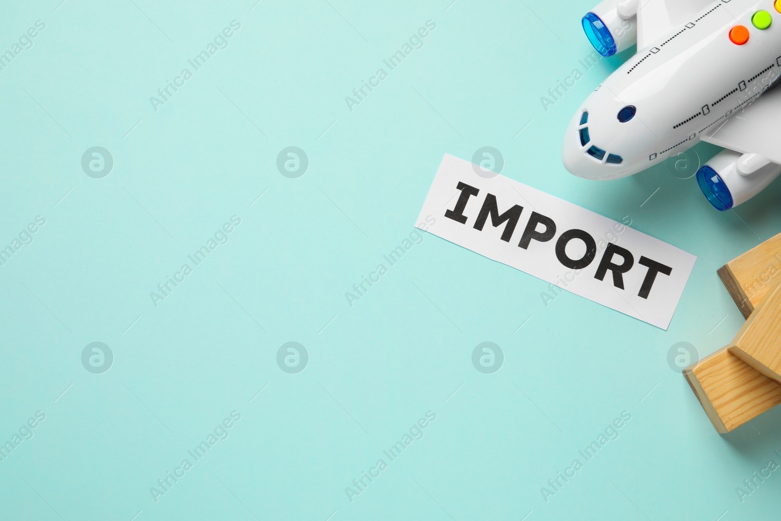 Photo of Import concept. Flat lay composition with toy plane and wooden cubes on light blue background. Space for text