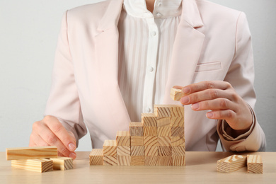 Woman building stairs at wooden table, closeup. Career promotion concept