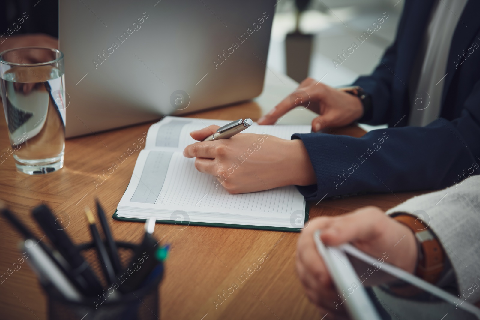 Photo of Woman writing in notebook at table during business meeting, closeup. Management consulting