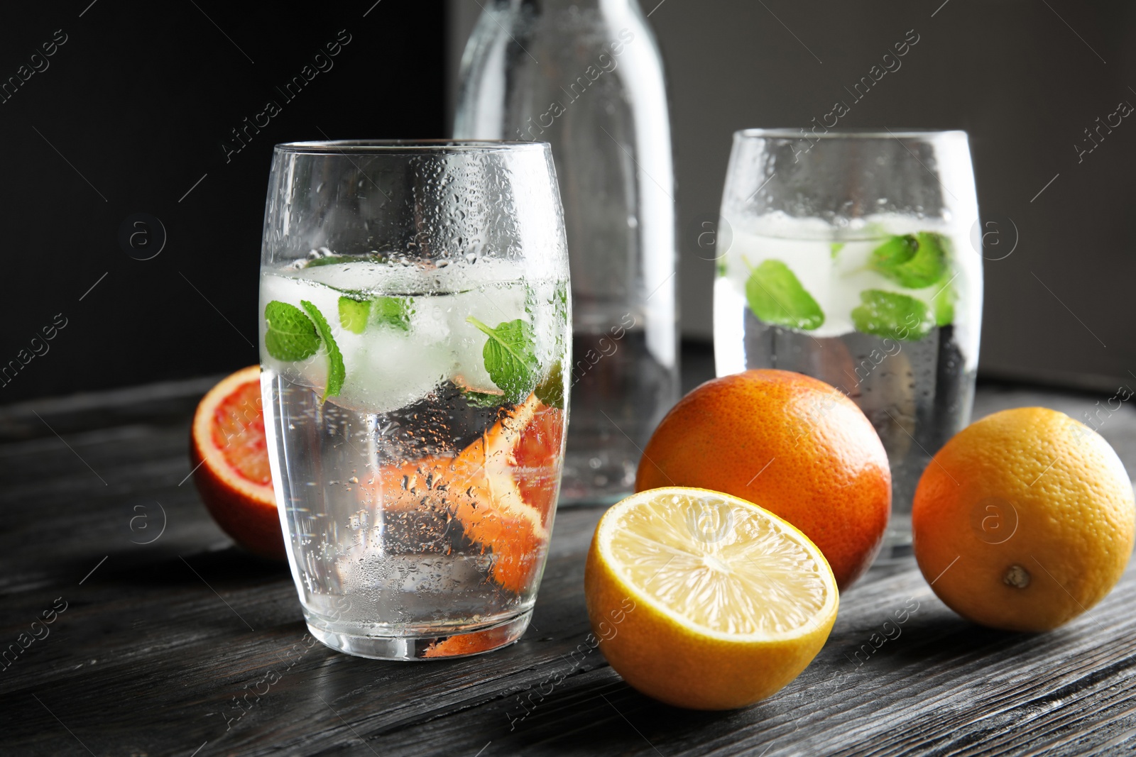 Photo of Composition with refreshing drink with mint and ice cubes in glass on dark table