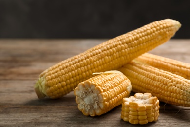 Photo of Tasty ripe corn cobs on wooden table