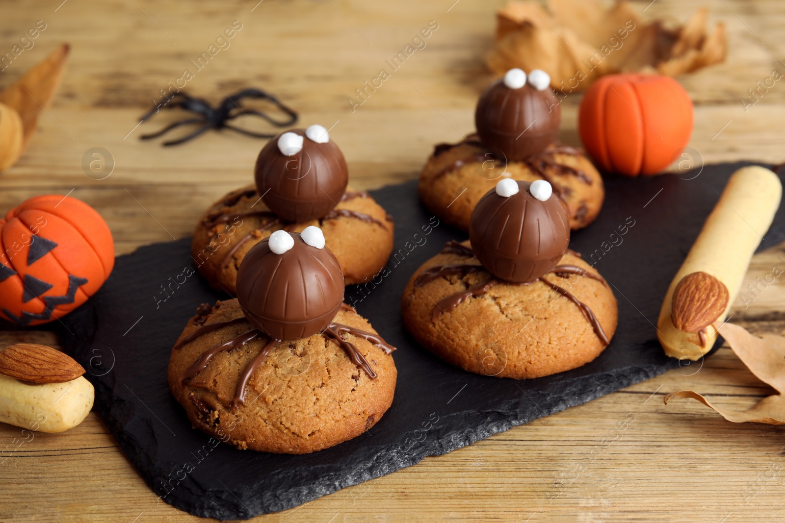 Photo of Delicious cookies decorated as monsters on wooden table, closeup. Halloween treat