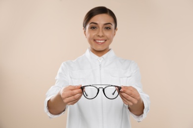 Photo of Female ophthalmologist with eyeglasses on light background