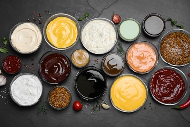 Photo of Many different sauces on black table, flat lay