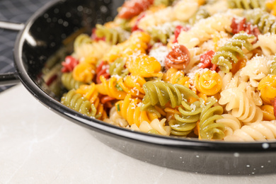 Colorful pasta with cheese on light grey marble table, closeup