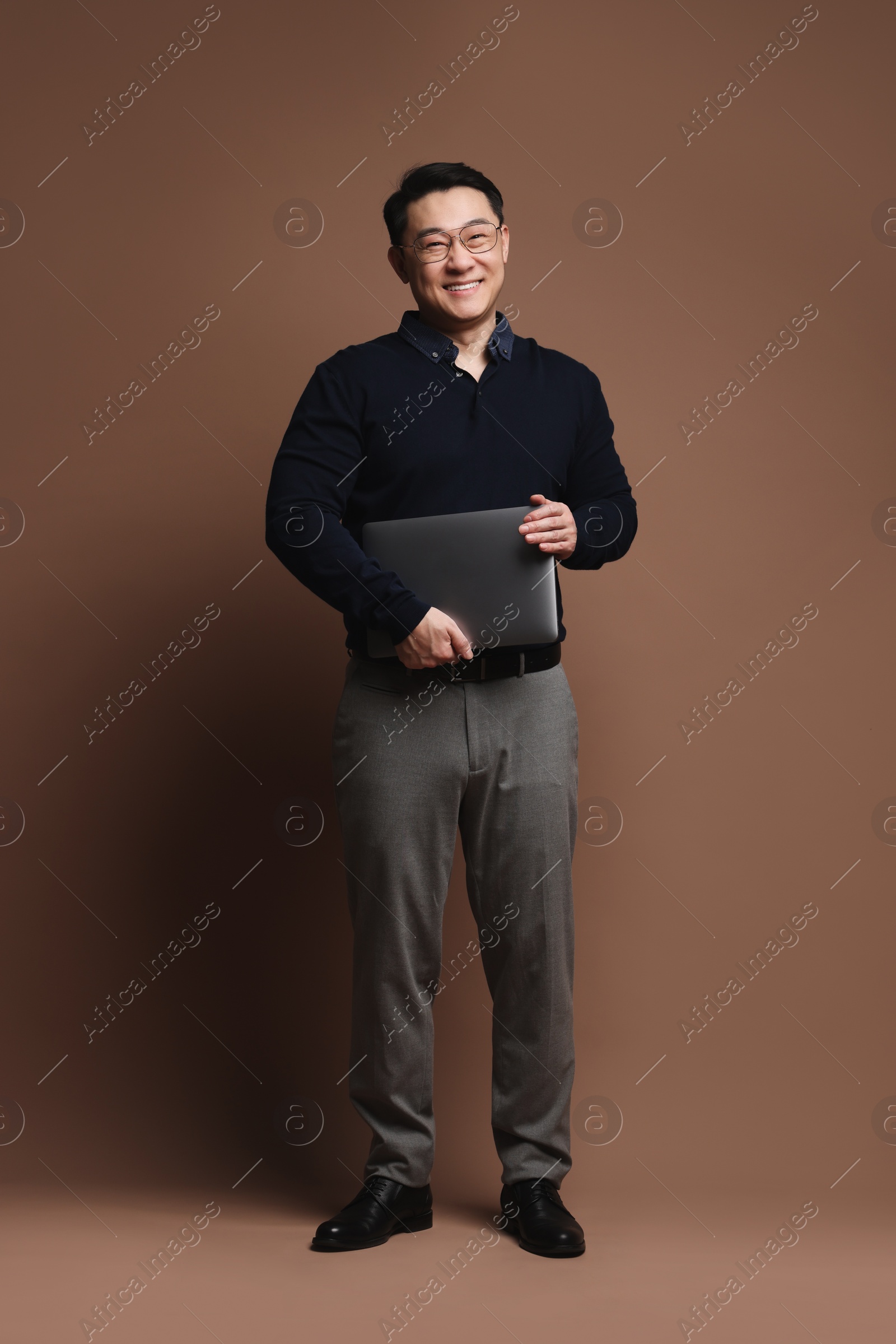 Photo of Full length portrait of happy man with laptop on brown background