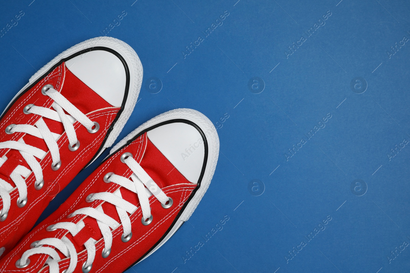 Photo of Pair of new stylish red sneakers on blue background, flat lay. Space for text