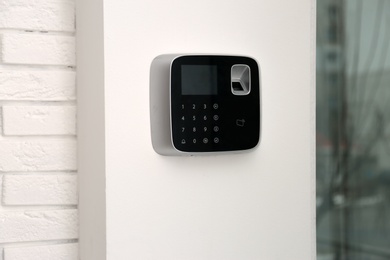 Modern alarm system with fingerprint scanner on white wall indoors