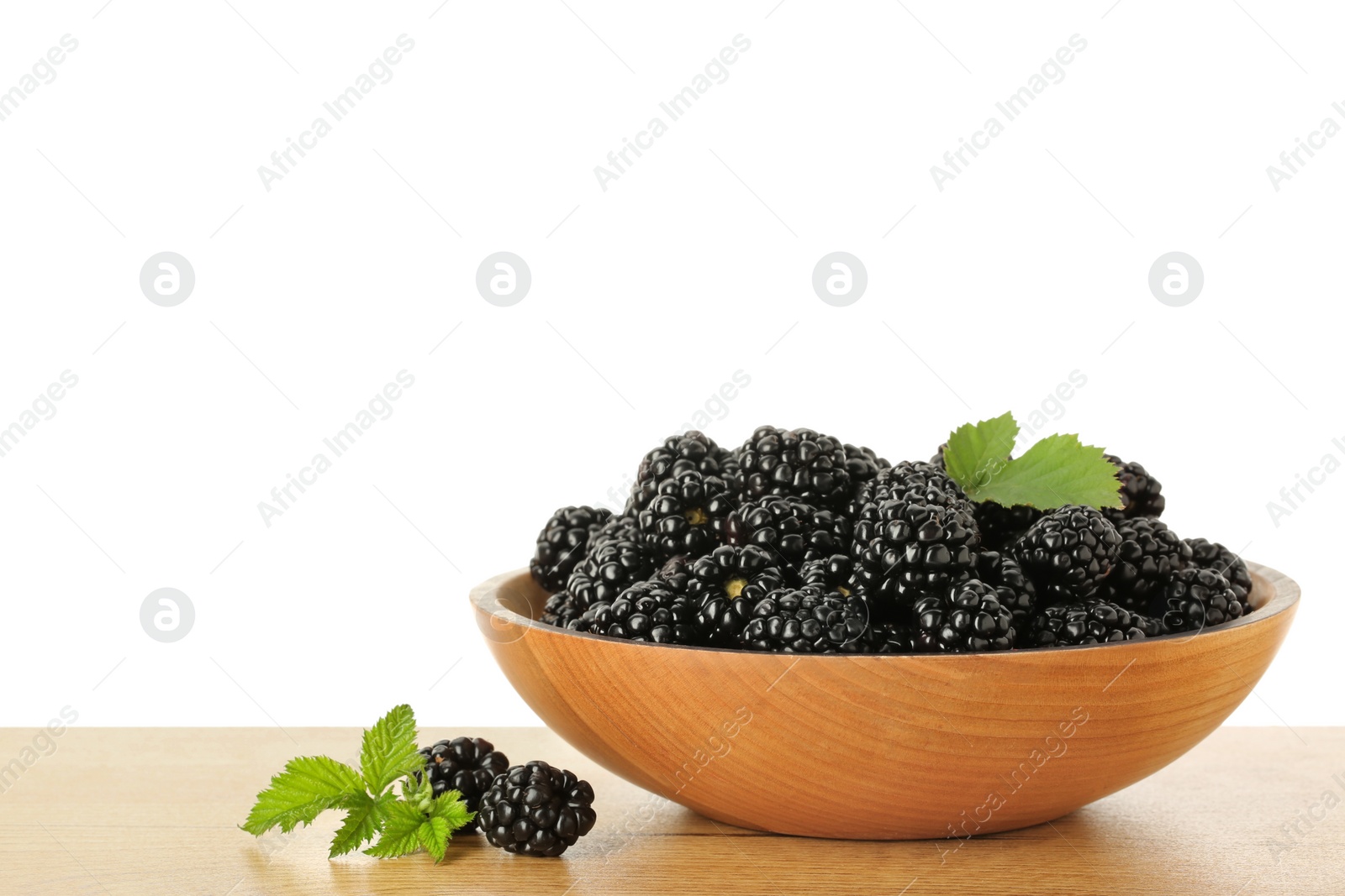 Photo of Bowl and fresh ripe blackberries on wooden table against white background, space for text