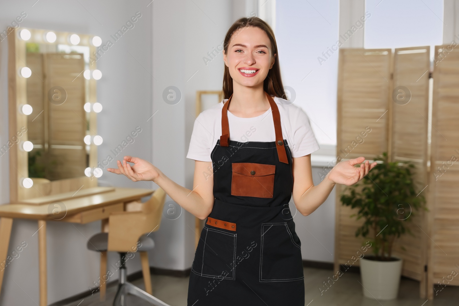 Photo of Portrait of professional hairdresser wearing apron in beauty salon