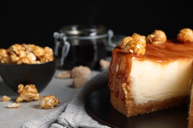 Sliced delicious cheesecake with caramel and popcorn on light grey table, closeup. Space for text