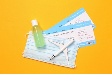 Flat lay composition with tickets and protective mask on yellow background. Travel during quarantine