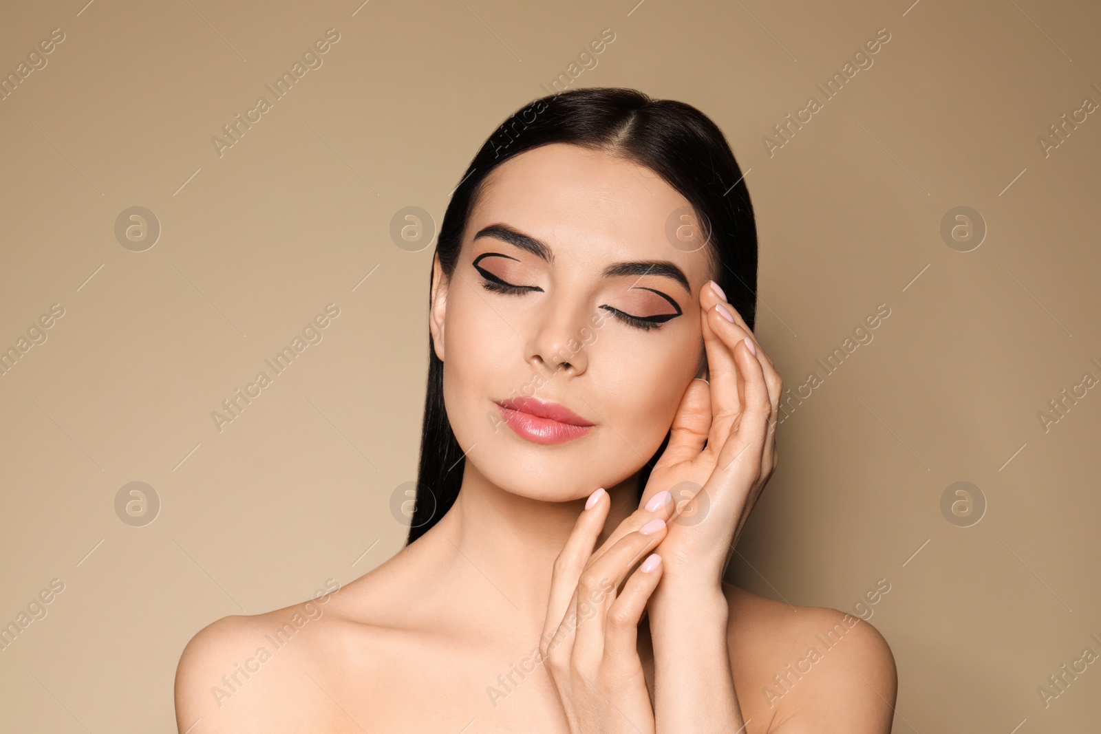 Photo of Beautiful woman with black eyeliner on beige background