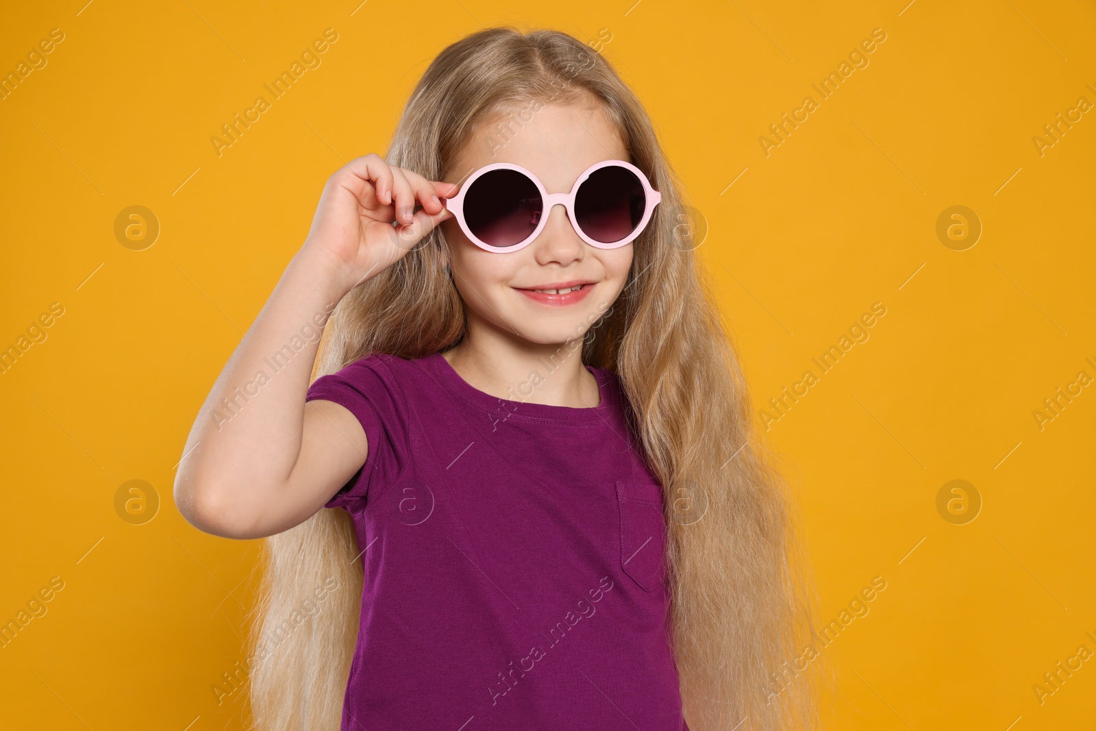 Photo of Girl in stylish sunglasses on orange background