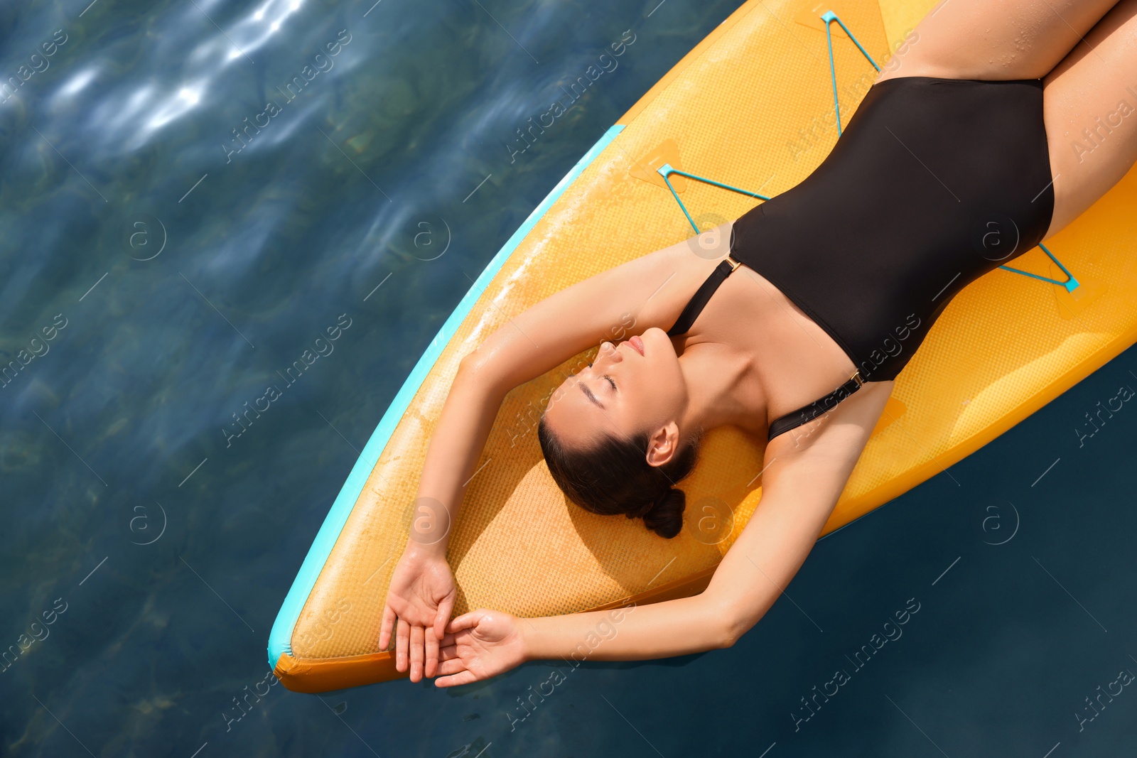 Photo of Young woman lying on SUP board in sea, top view. Space for text