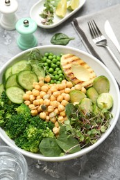 Photo of Healthy meal. Tasty vegetables and chickpeas in bowl on grey table