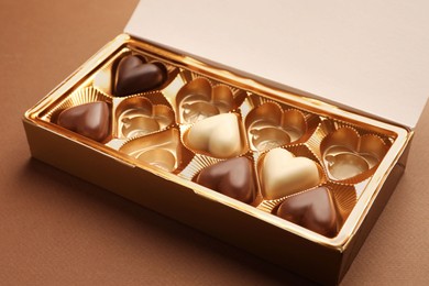 Partially empty box of chocolate candies on brown background, closeup