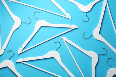 Photo of White hangers on light blue background, flat lay