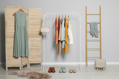 Photo of Stylish room interior with clothes rack and folding screen