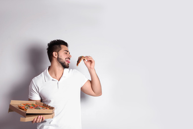 Handsome man with pizza on white background, space for text