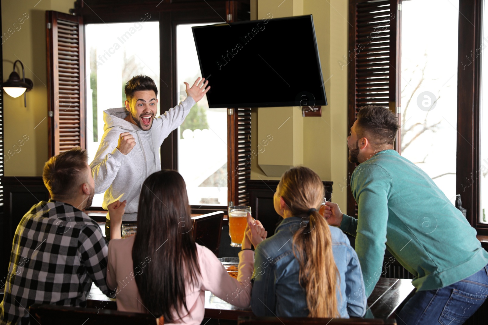 Photo of Group of friends watching football in sport bar, back view