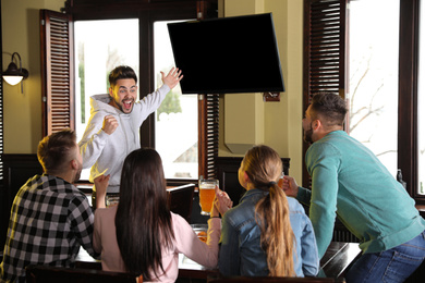 Group of friends watching football in sport bar, back view