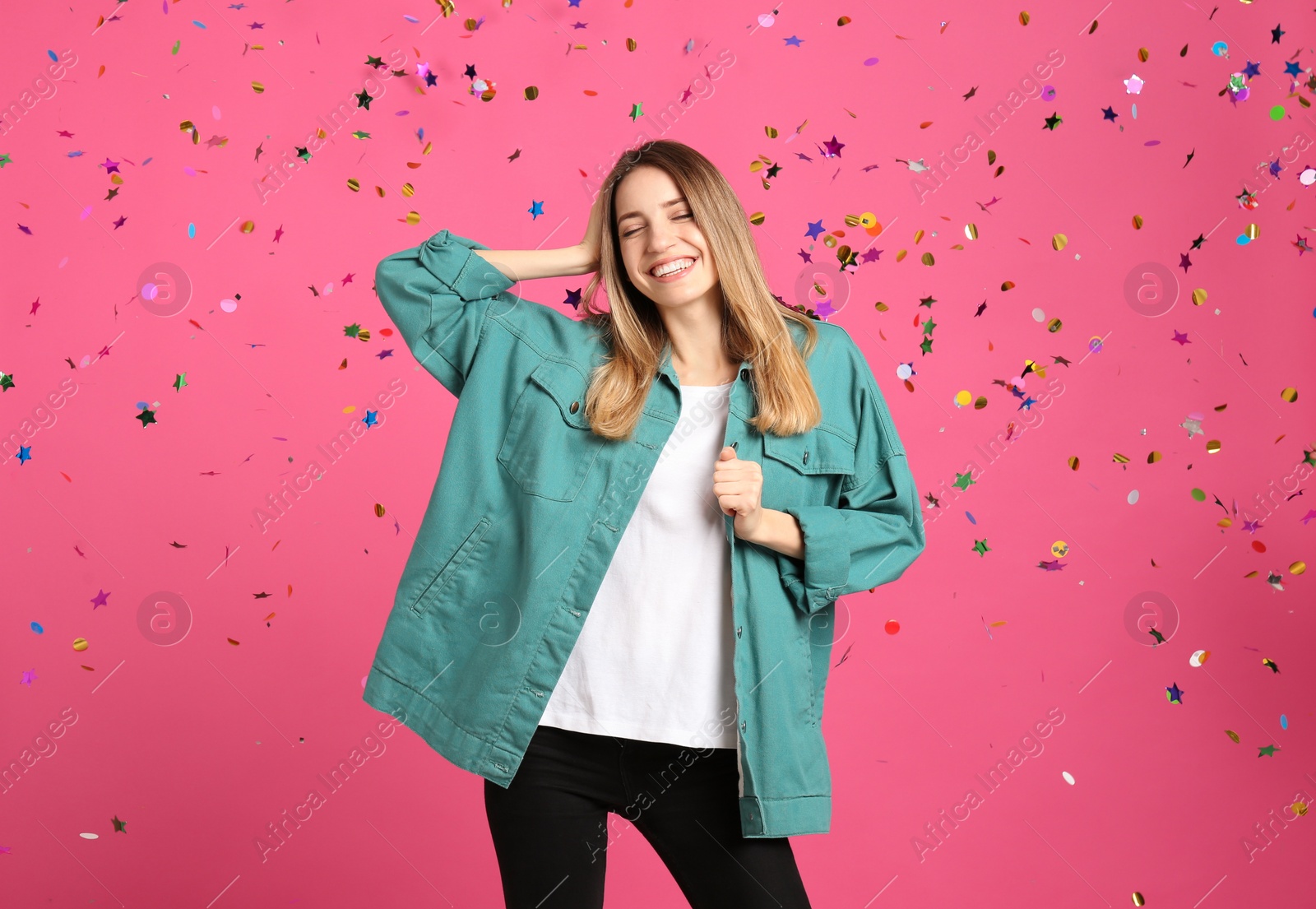 Photo of Happy woman and falling confetti on pink background