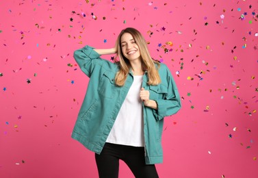 Photo of Happy woman and falling confetti on pink background