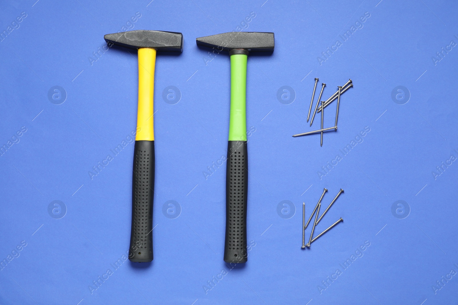 Photo of Hammers and metal nails on blue background, top view