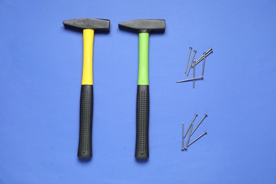 Hammers and metal nails on blue background, top view