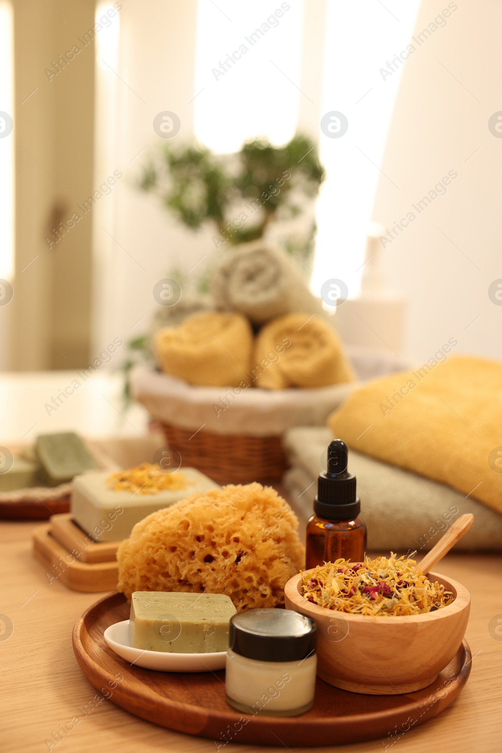 Photo of Dry flowers, loofah, soap bar, bottle of essential oil and jar with cream on wooden table indoors, space for text. Spa time