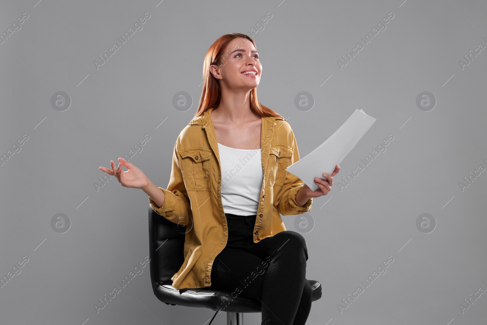 Photo of Casting call. Young woman with script performing on grey background