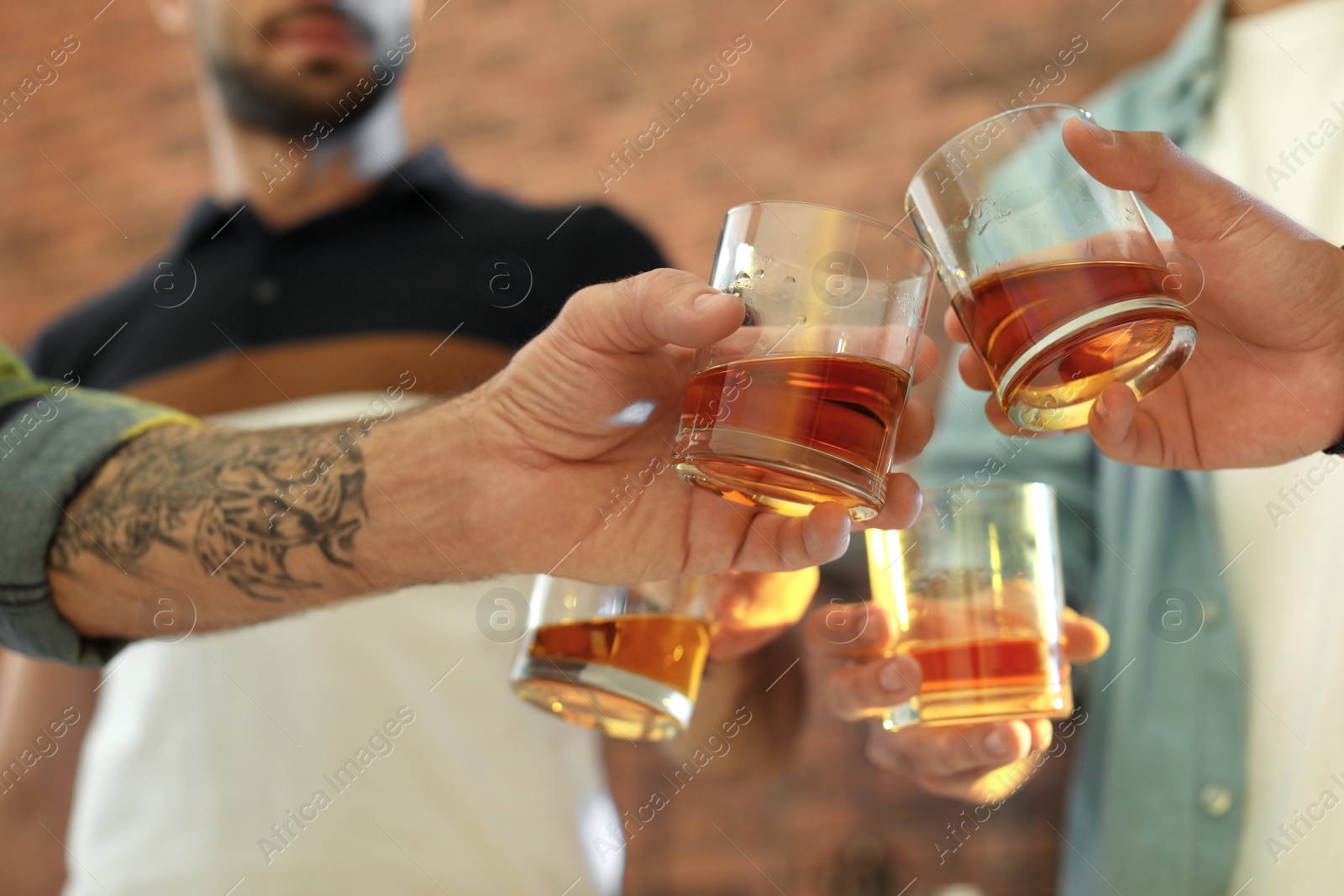 Photo of Friends toasting with glasses of whiskey indoors, closeup