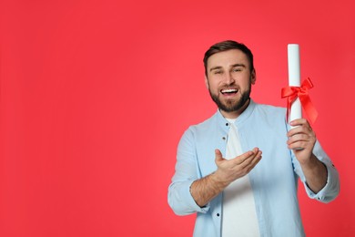 Photo of Happy student with diploma on red background. Space for text