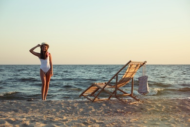 Photo of Young woman near deck chair on beach