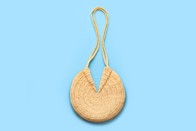 Elegant woman's straw bag on light blue background, top view